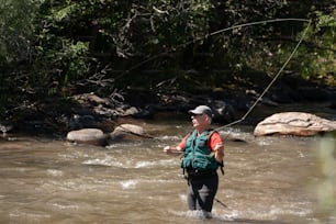 a man standing in a river while holding a fishing rod