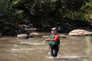 a man standing in a river holding a fishing rod