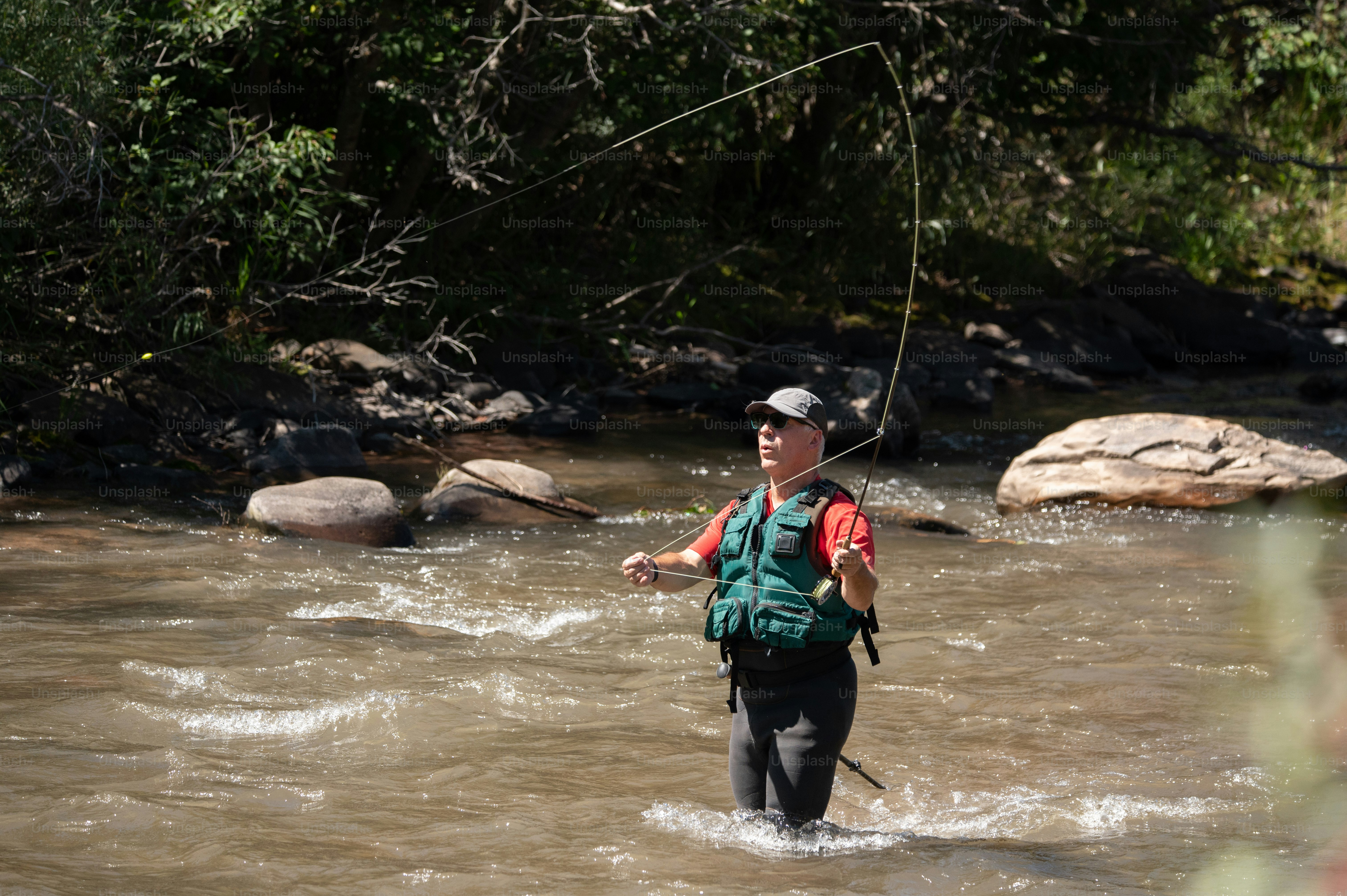 Ein Mann, der in einem Fluss steht und eine Angelrute hält