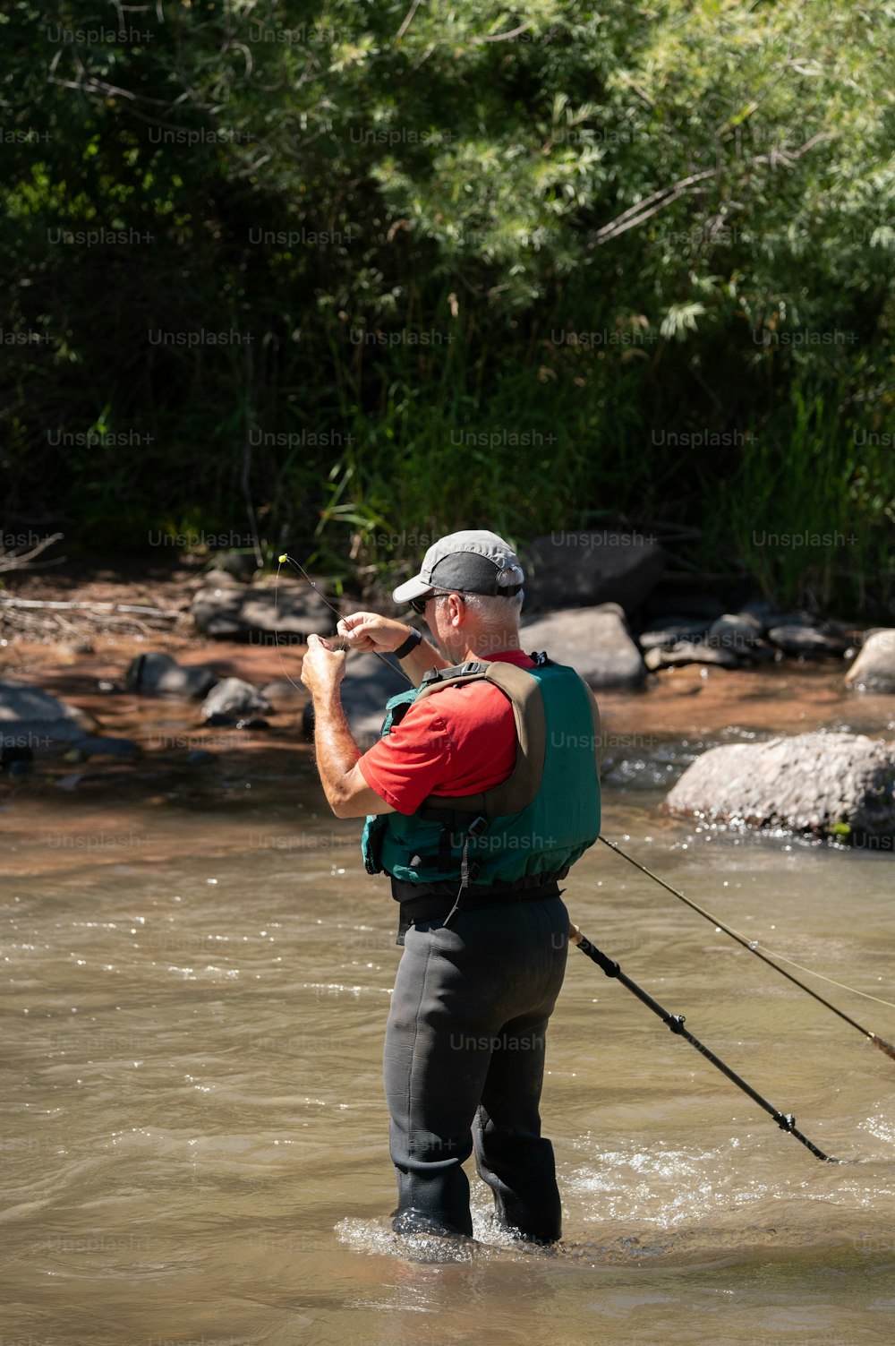 um homem parado em um rio segurando uma vara de pesca