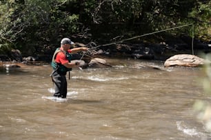 Un homme debout dans une rivière tenant une ligne de pêche