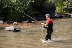 um homem parado em um rio segurando uma vara de pesca