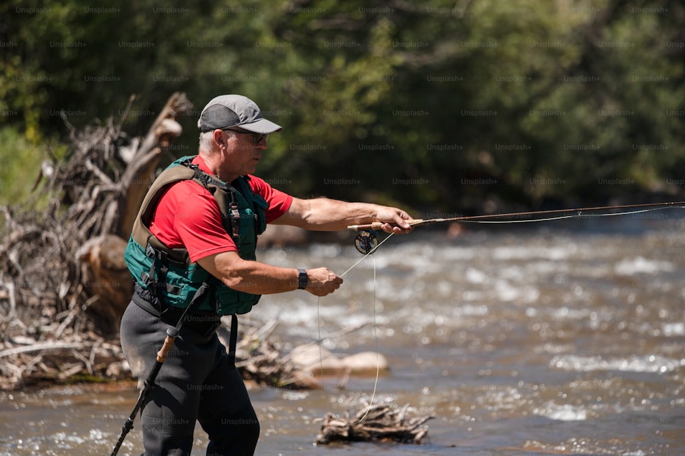 Un uomo in piedi in un fiume che tiene una canna da pesca