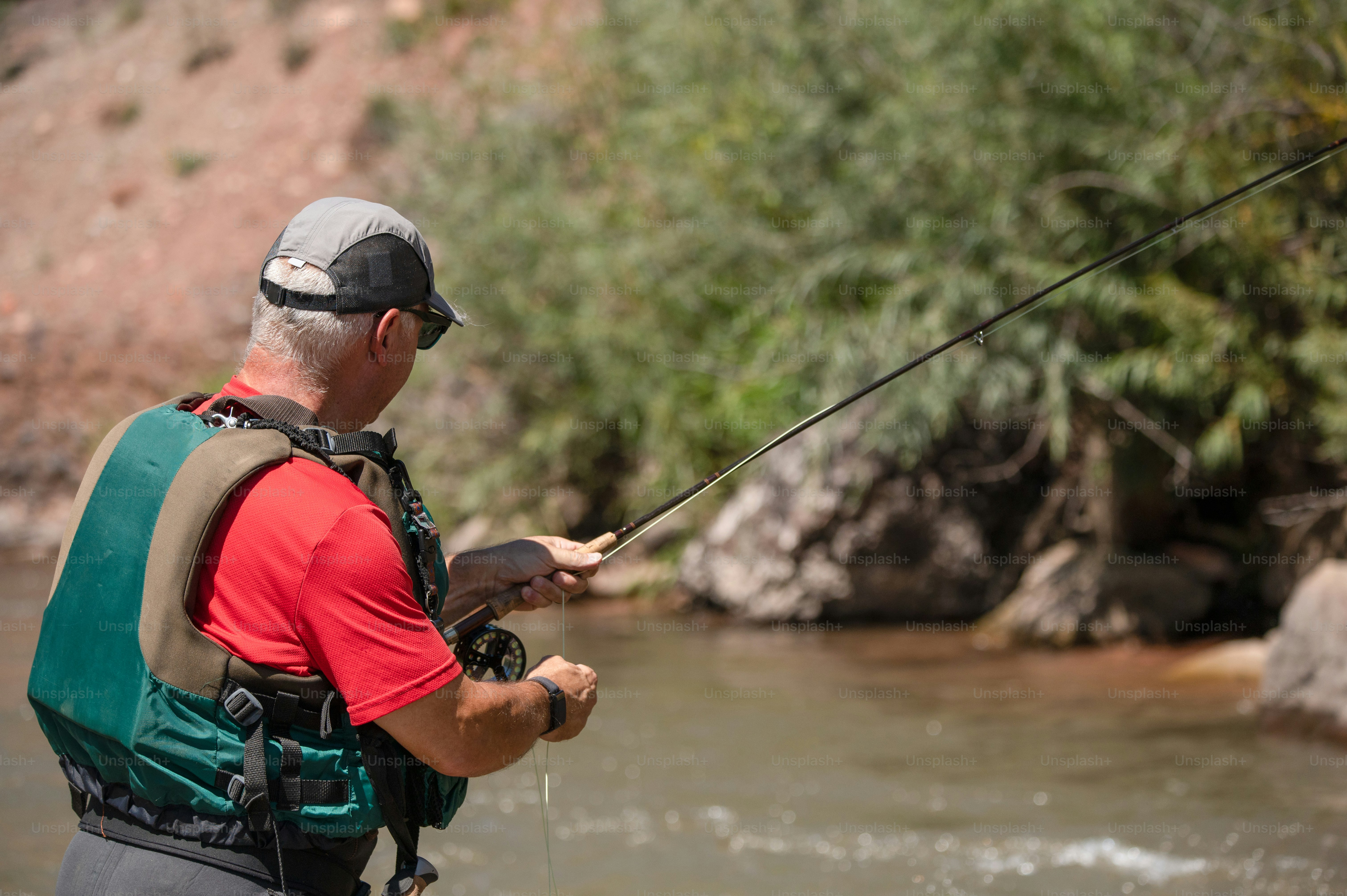 a man in a red shirt is fishing in a river