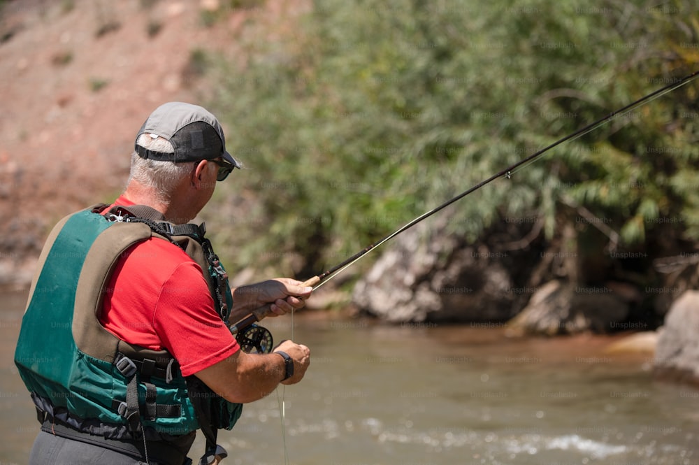 Ein Mann in einem roten Hemd fischt in einem Fluss