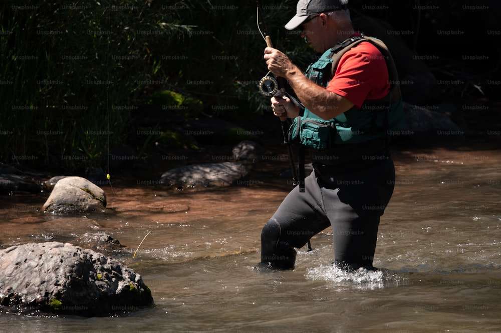 um homem parado em um rio segurando uma câmera
