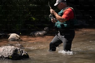 Ein Mann, der in einem Fluss steht und eine Kamera hält
