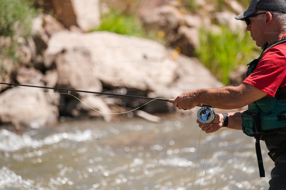 a man holding a fishing rod while standing next to a river