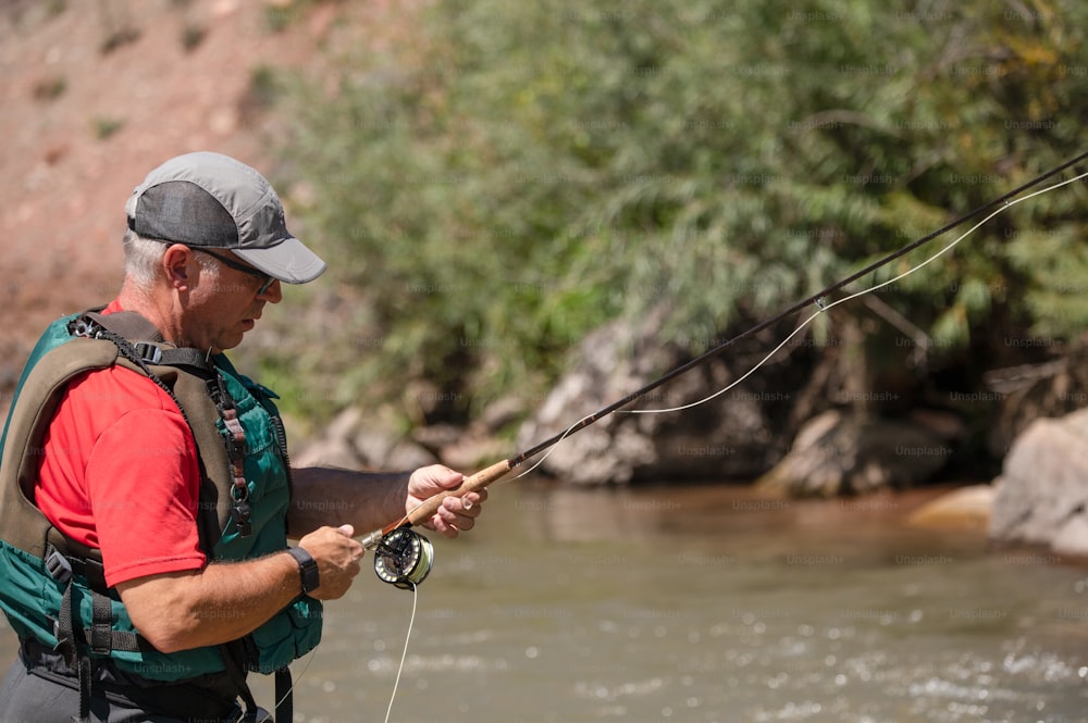 um homem segurando uma vara de pesca enquanto estava em pé em um rio
