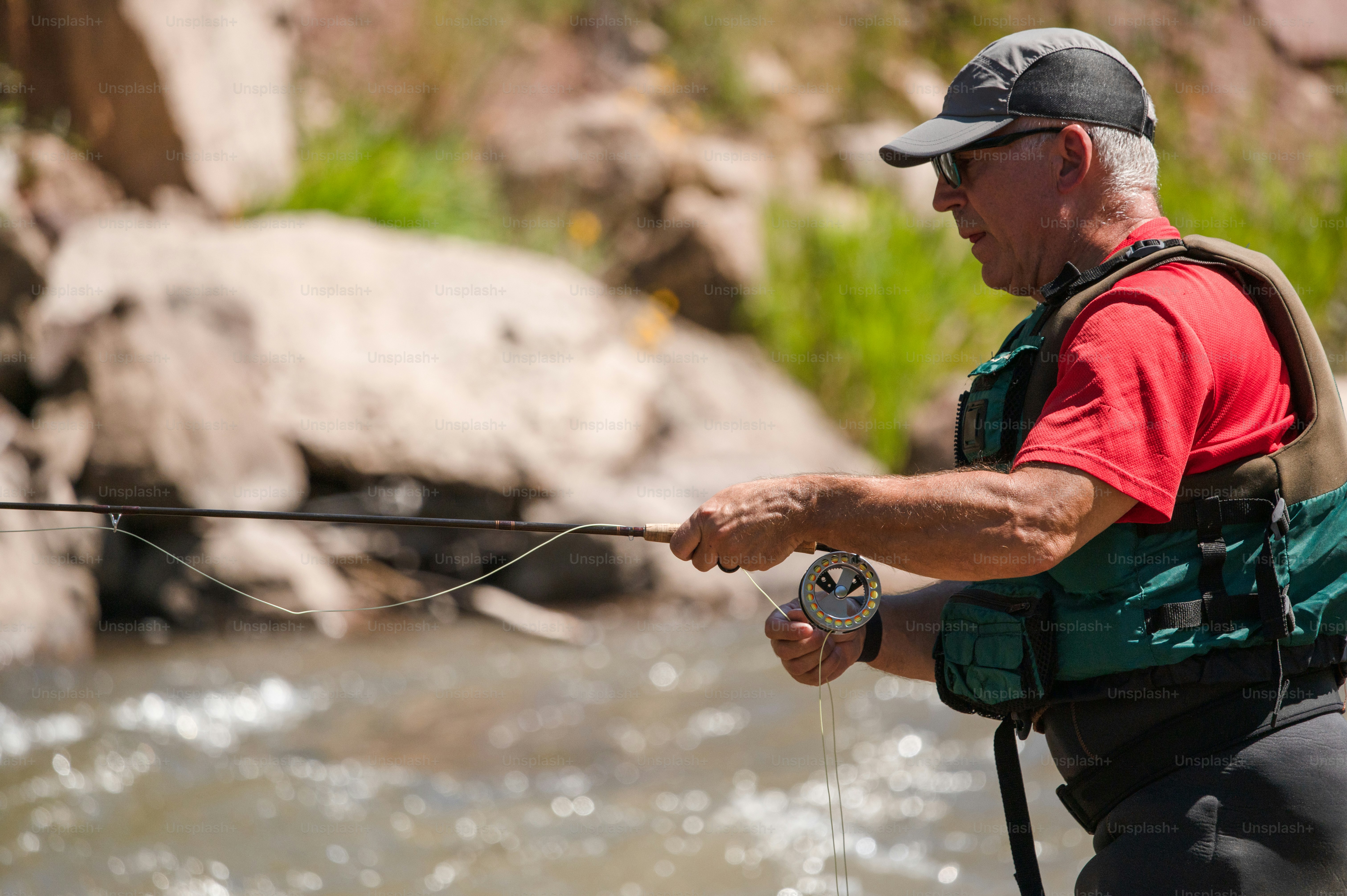 川のほとりに立って釣り竿を持つ男