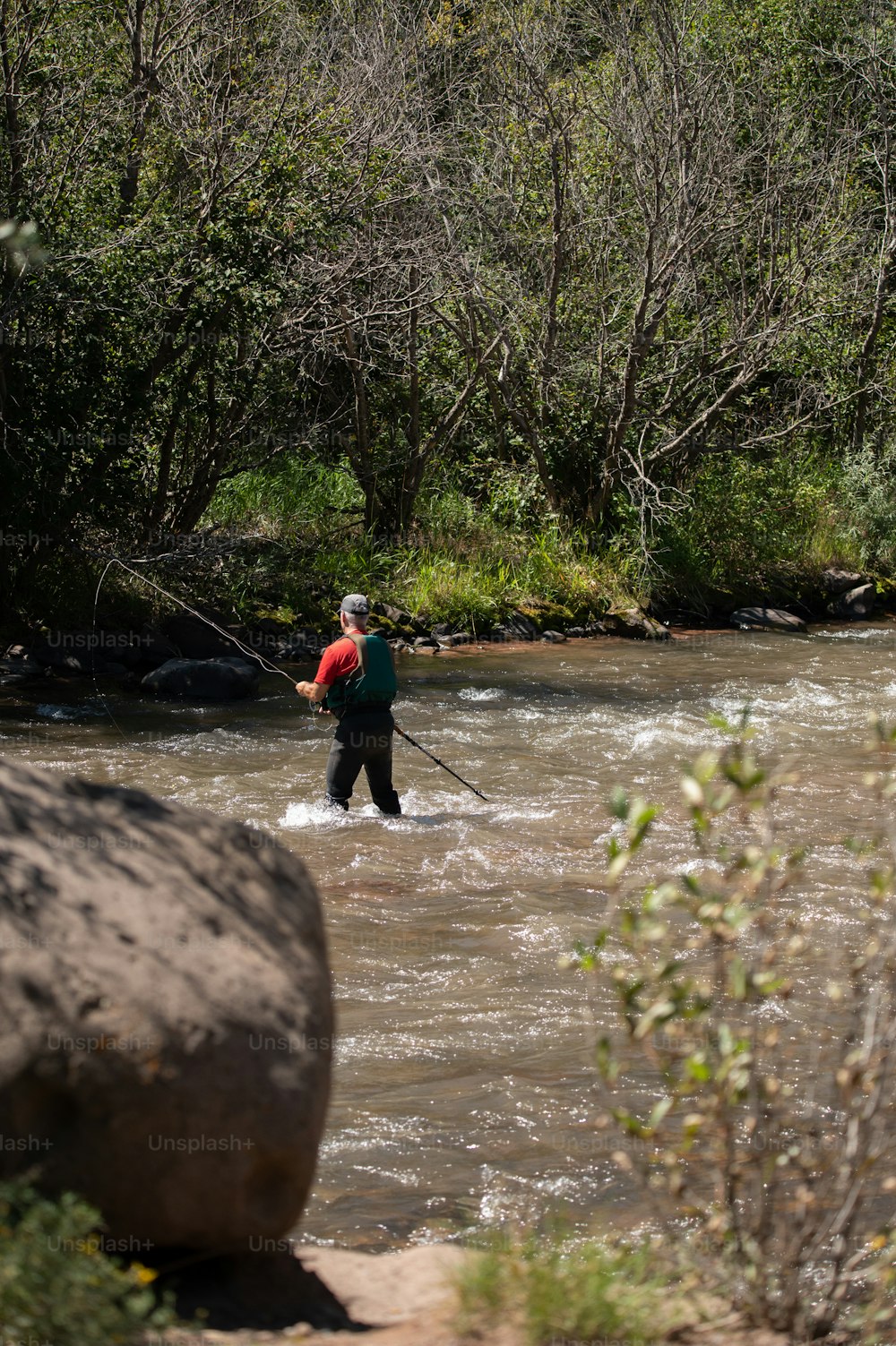a man standing in a river holding a fishing pole