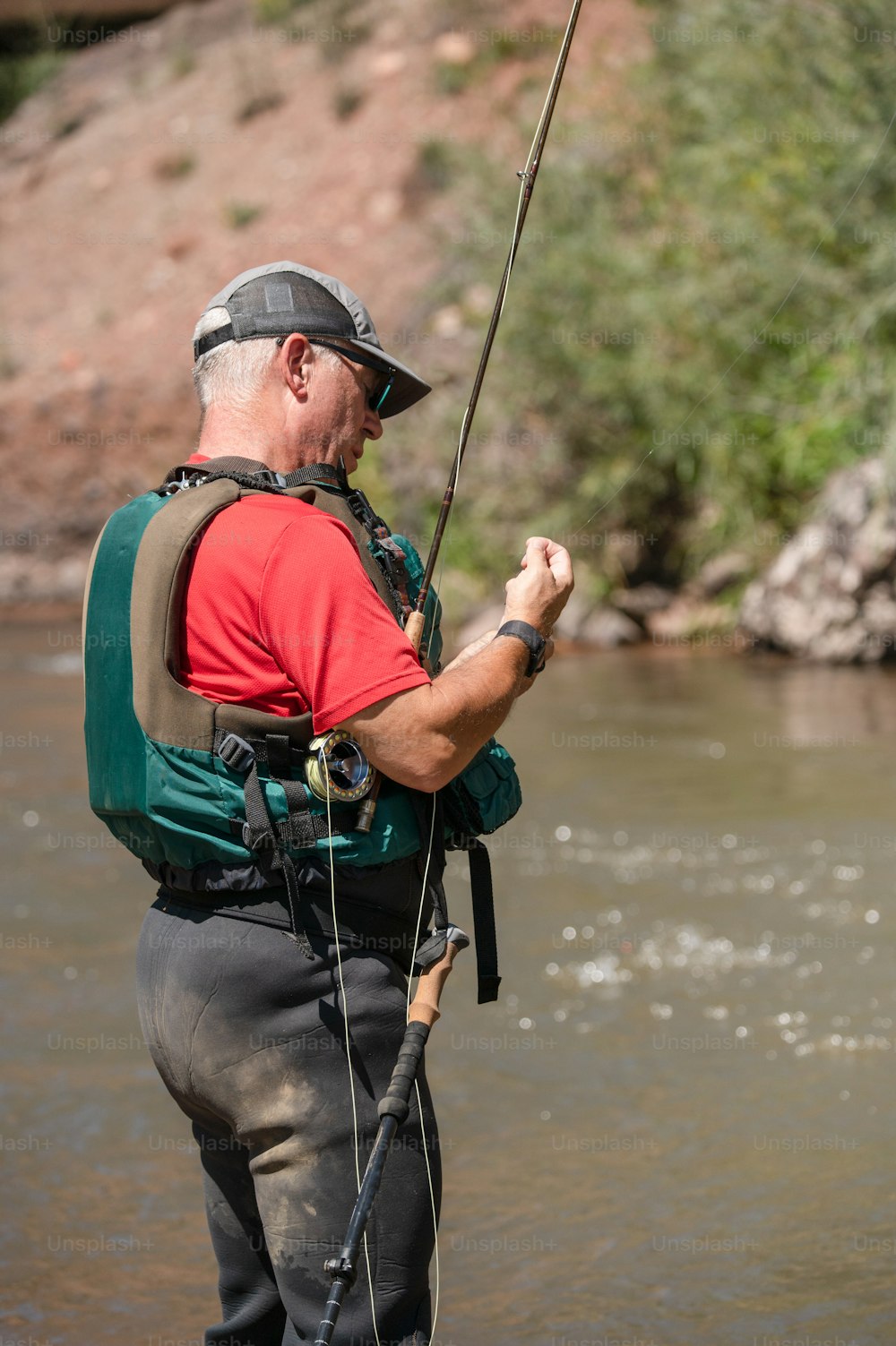 Un homme debout dans une rivière tenant une canne à pêche