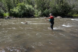 a man standing in a river holding a fishing rod