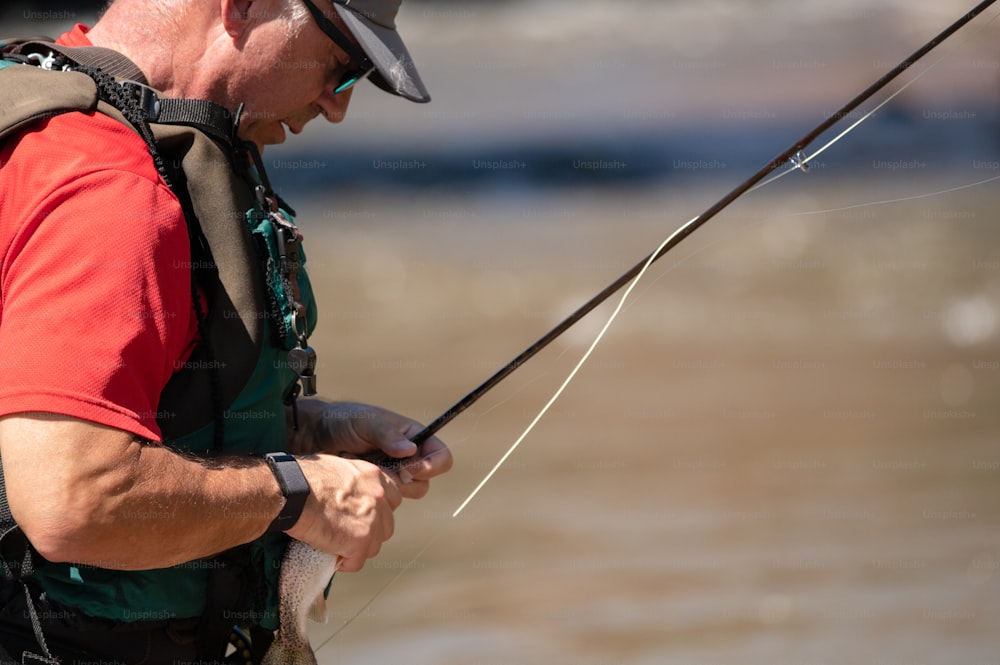 a man holding a fish while standing next to a body of water