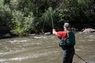 Un homme debout dans une rivière tenant une ligne de pêche