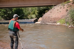 a man standing in a river while holding a fishing rod