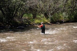 a man standing in a river holding a fishing pole