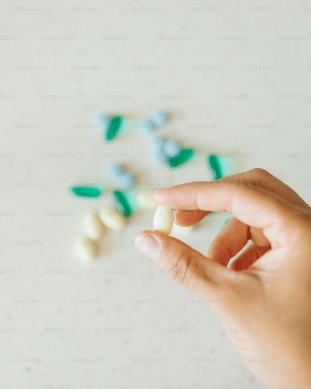 a hand is holding a small pill with green and white pills
