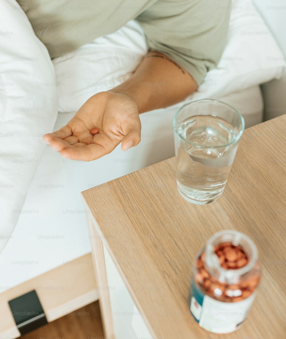 a person sitting on a bed with a glass of water