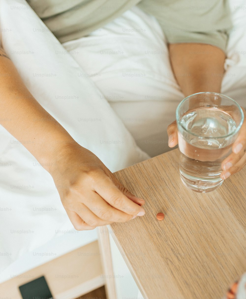 a person holding a glass of water on a bed