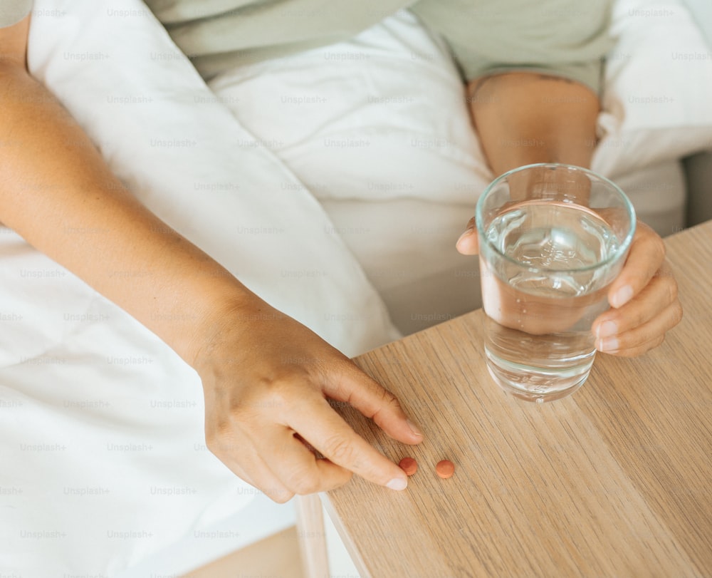 a person holding a glass of water on a bed