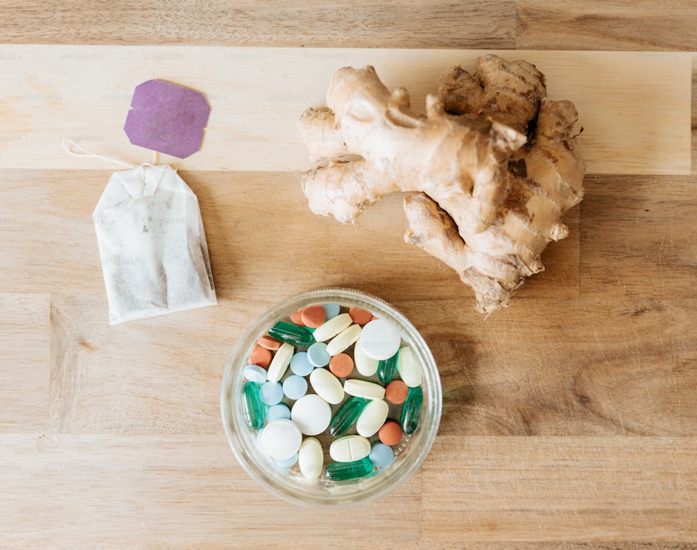 a bowl of pills and ginger root on a table