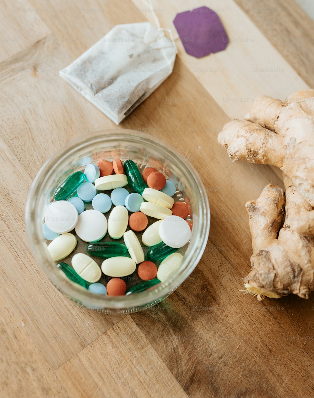 a bowl of pills and a ginger root on a table