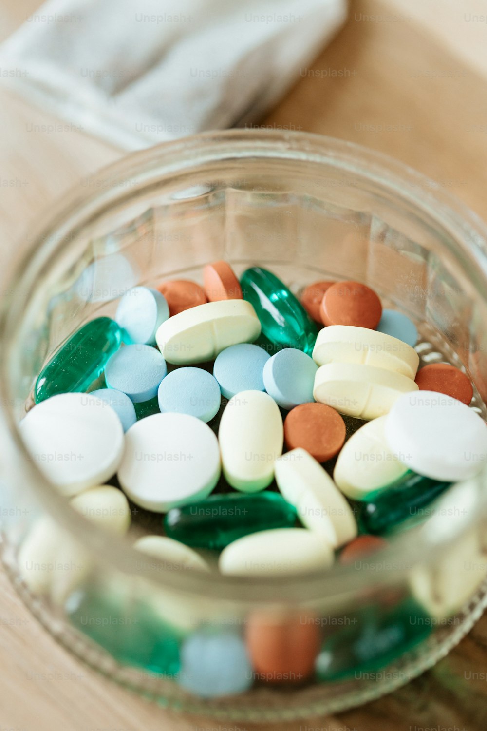 a glass bowl filled with pills on top of a wooden table