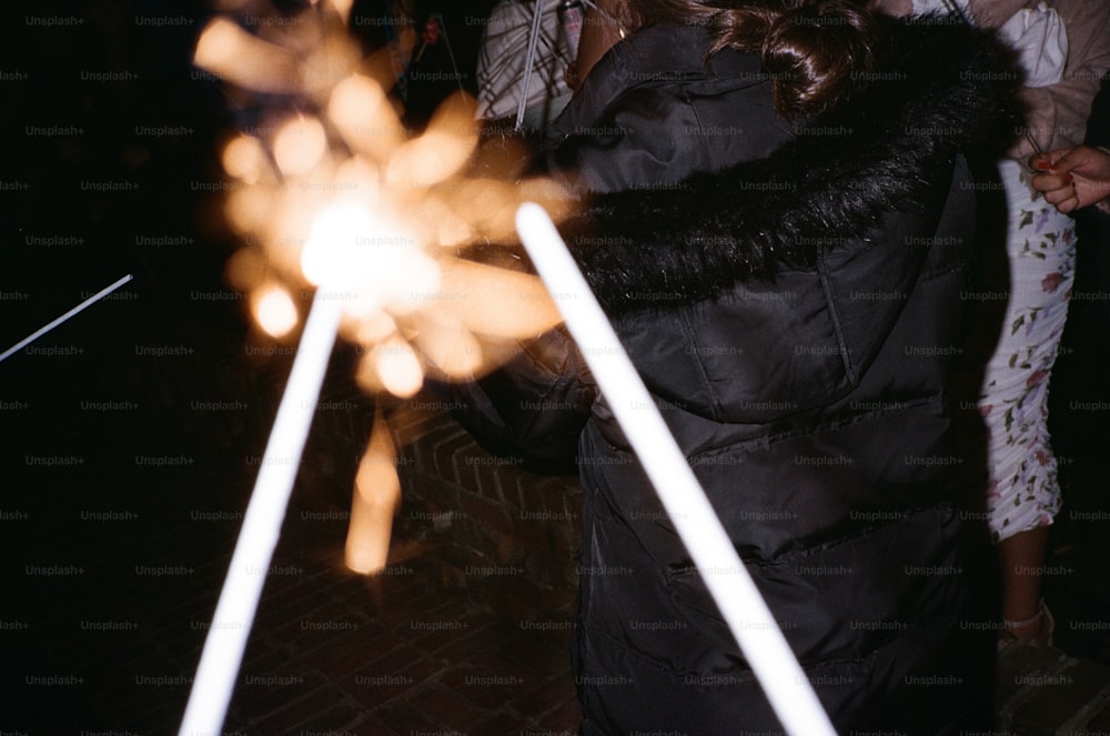 a woman in a black coat holding a sparkler