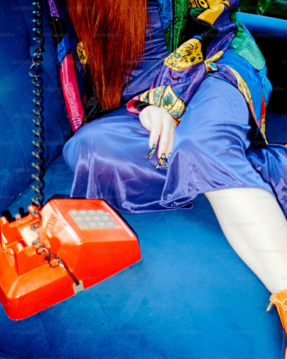 a woman in a blue dress sitting on a blue couch