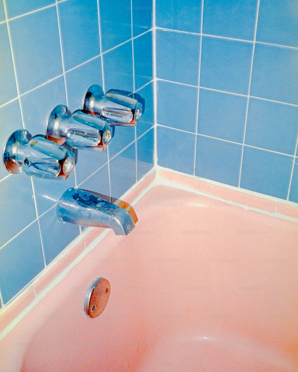 una bañera rosa con paredes de azulejos azules y azulejos azules