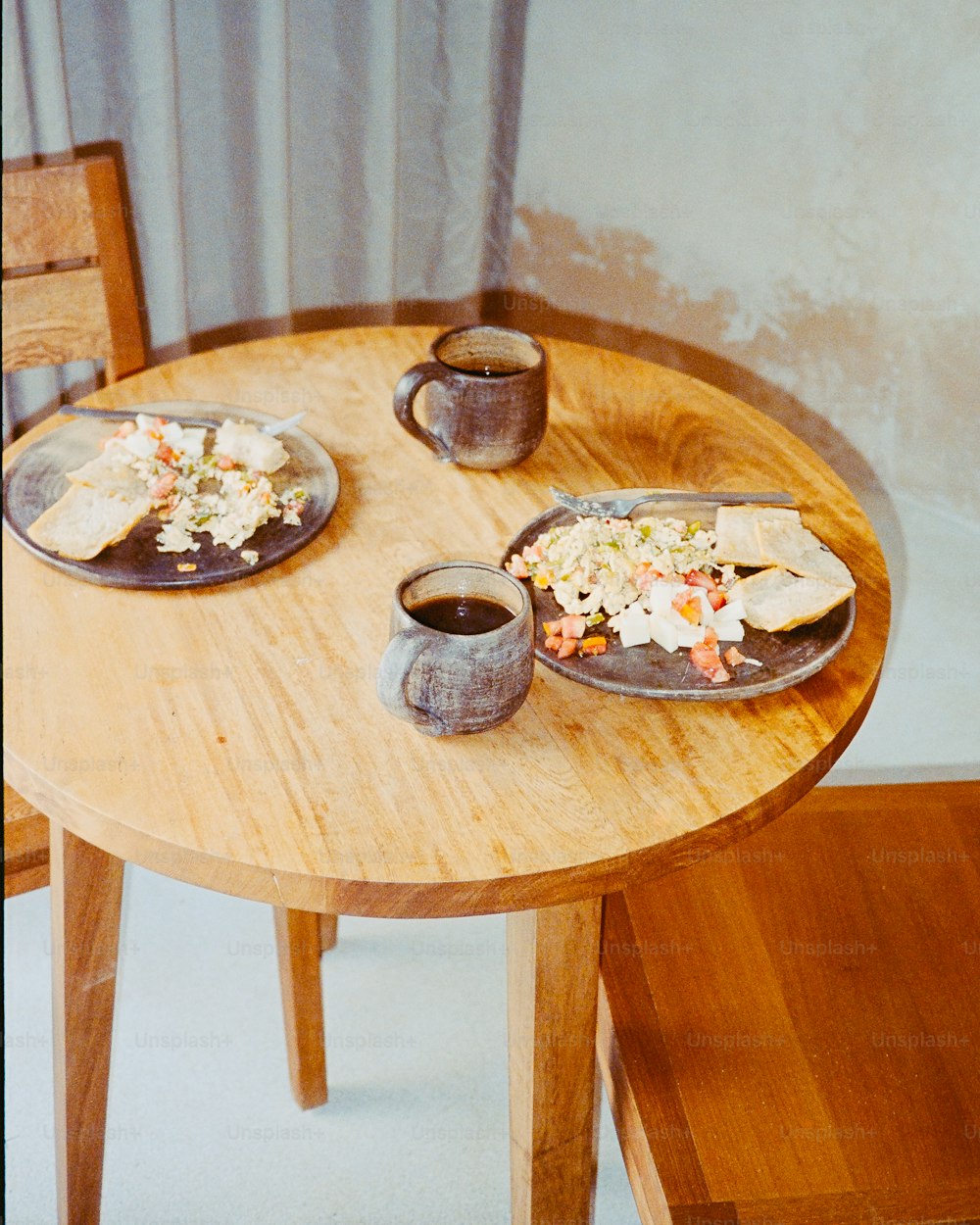a wooden table topped with two plates of food