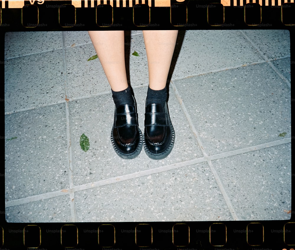 Una persona che indossa scarpe nere in piedi su un pavimento di piastrelle