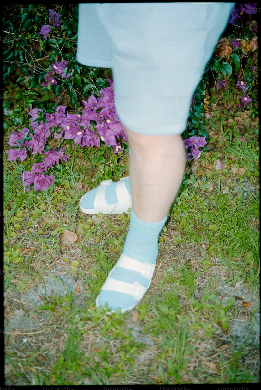 uma pessoa vestindo meias azuis e brancas em pé na grama