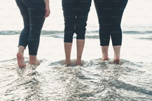three people standing in the water at the beach