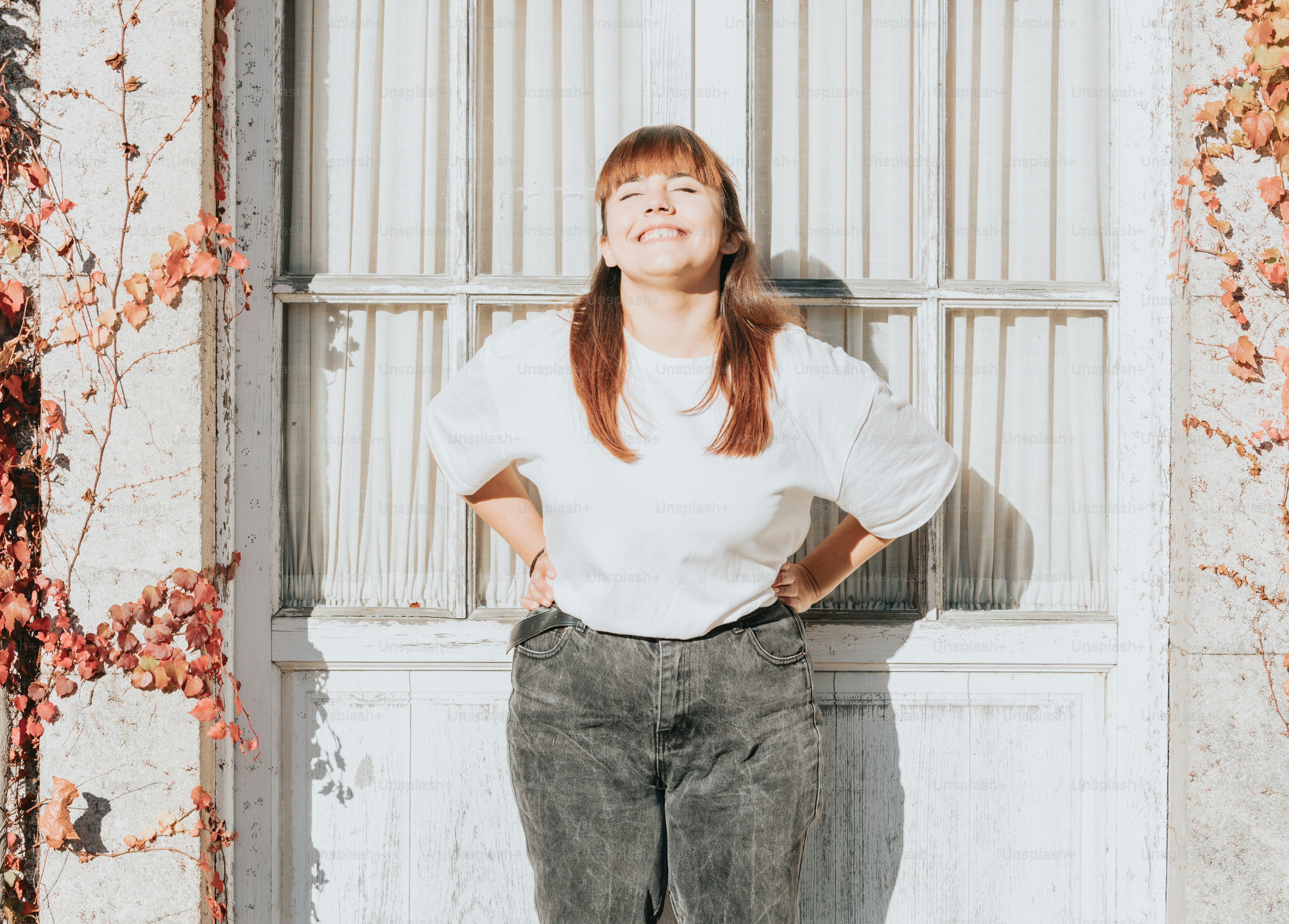 Une femme debout devant une fenêtre, les mains sur les hanches