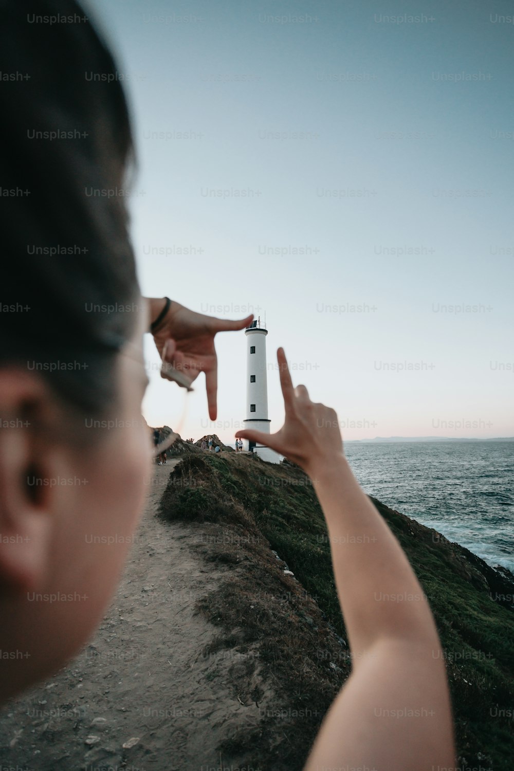 a person pointing at a lighthouse on a cliff