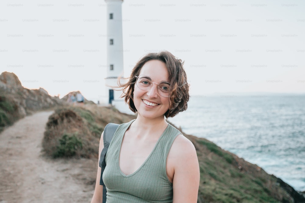Une femme debout sur un chemin près d’un phare