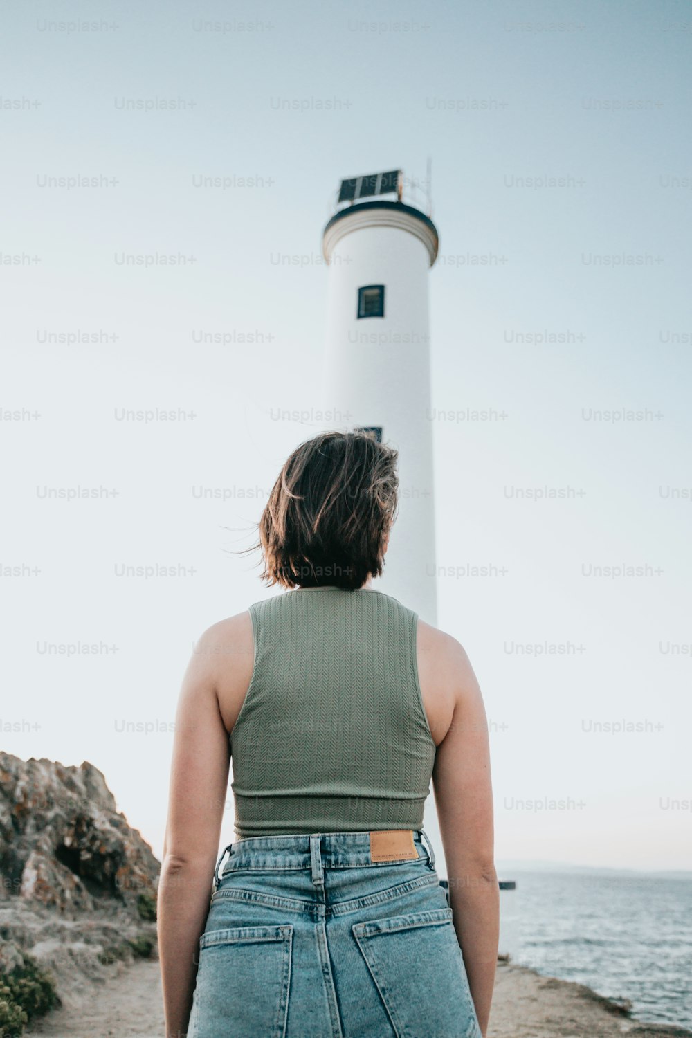a woman standing in front of a light house
