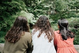 three girls sitting on a bench looking at the woods