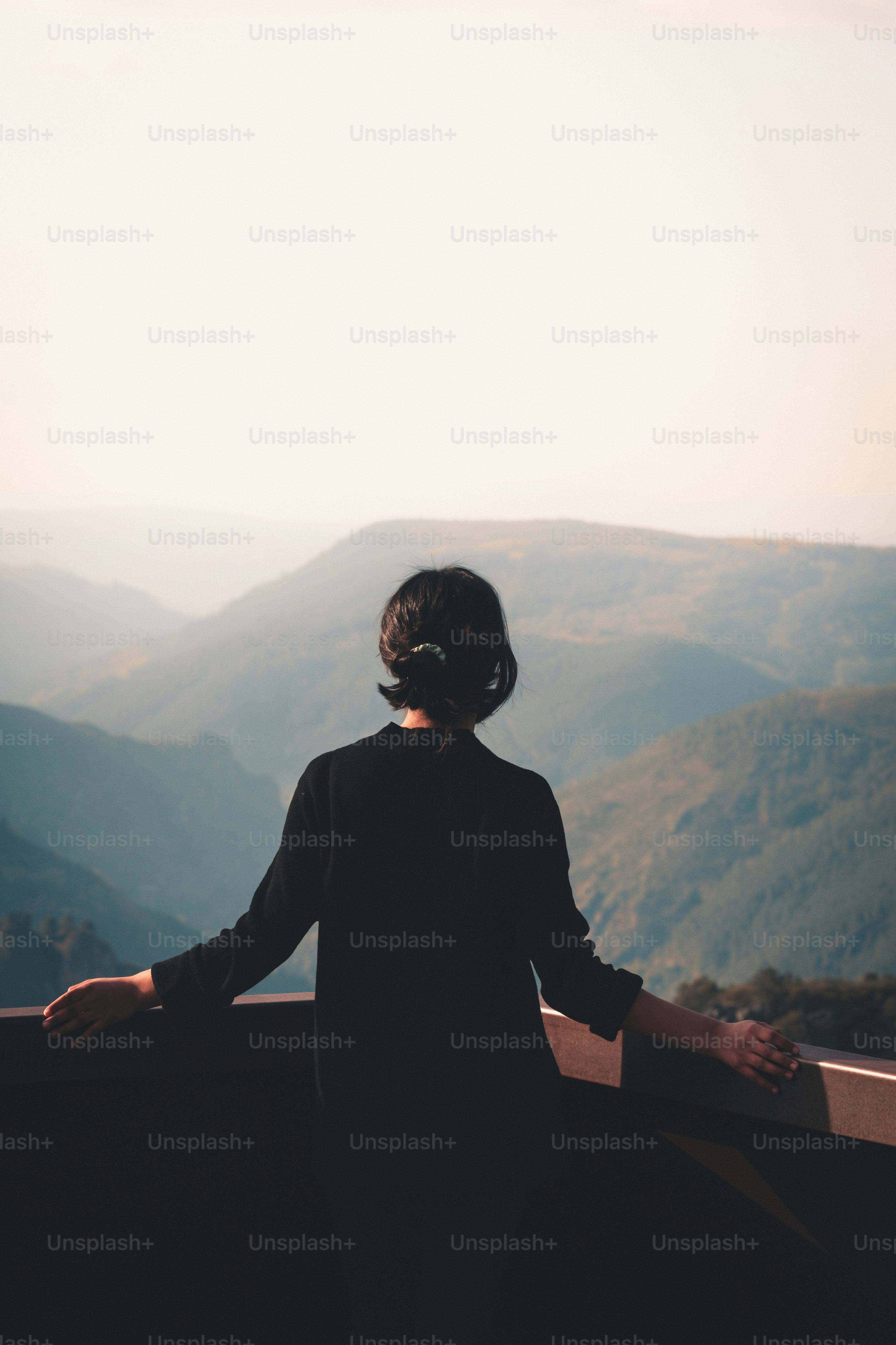 a woman standing on top of a mountain overlooking a valley