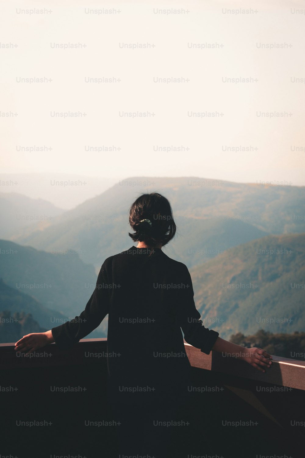 uma mulher no topo de uma montanha com vista para um vale