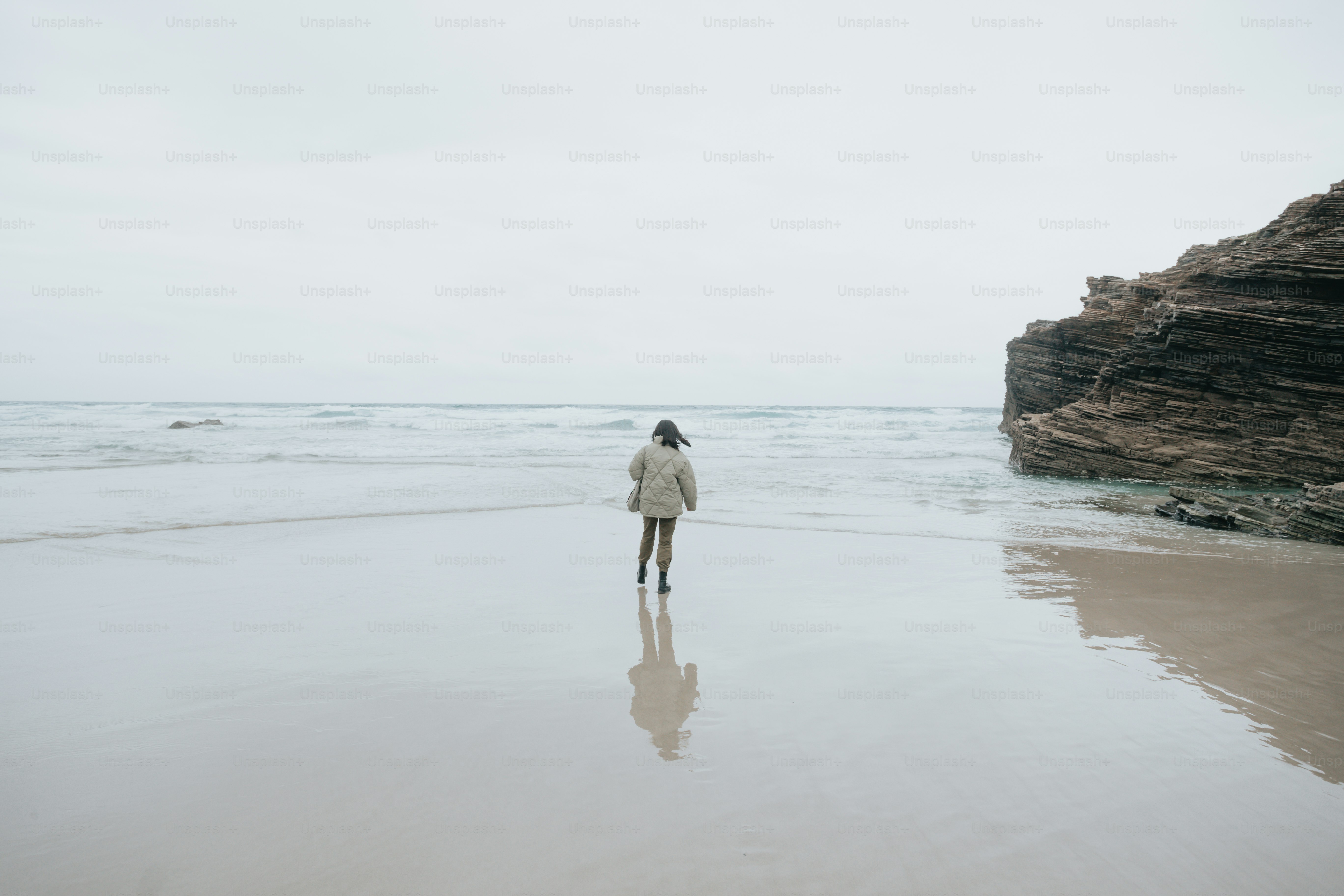 A woman standing on top of a sandy beach next to the ocean photo ...