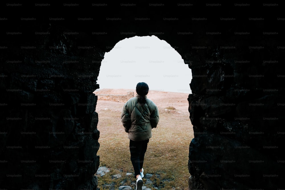 a person walking through a tunnel in a field