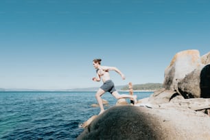 um homem correndo em uma praia rochosa ao lado do oceano