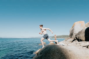 a man running on a rocky beach next to the ocean