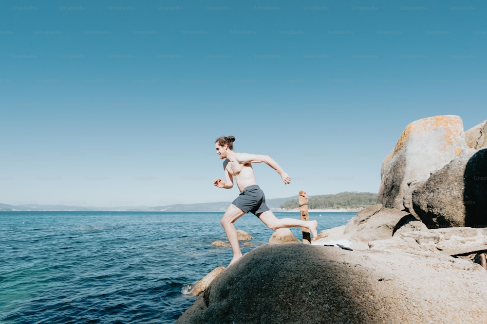 a man running on a rocky beach next to the ocean
