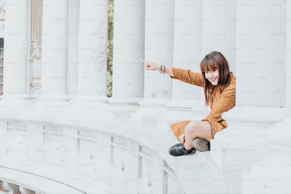 a woman sitting on a ledge pointing at something