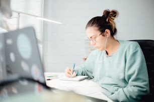 a woman sitting at a desk writing on a piece of paper