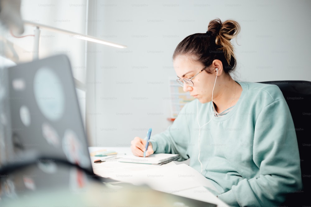 une femme assise à un bureau écrivant sur un morceau de papier